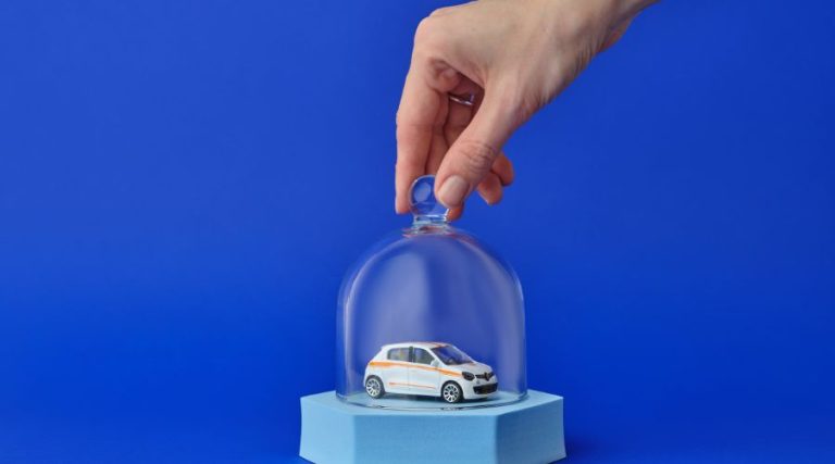 Main qui tient un contenant en verre pour encapsuler une voiture, illustrant le top 5 assurance auto à Gatineau
